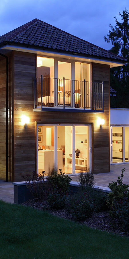 Image shows the outside of a house in the evening. Image depicts SureBuild Homes as experienced builders in Hitchin.