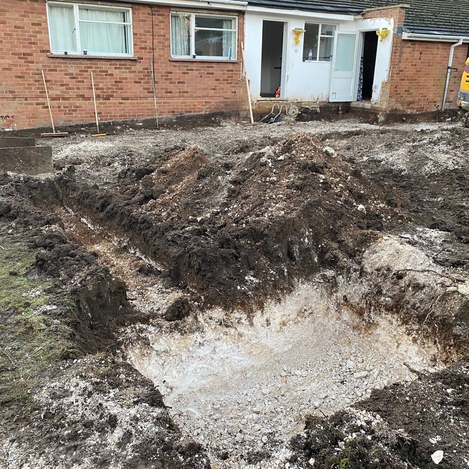 Image shows a digger and the ground works before a bungalow extension.